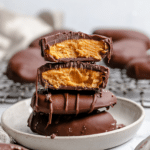 Healthy 4 ingredient Reese's eggs on a wooden table, showcasing the creamy peanut butter filling and dark chocolate coating.