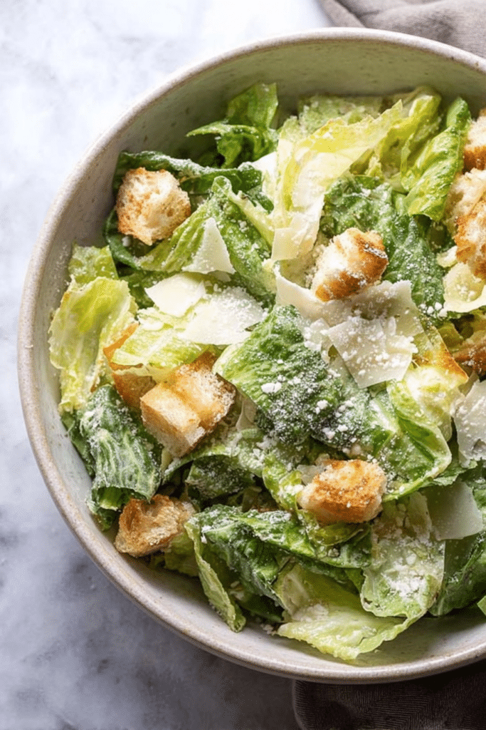 Delicious homemade Caesar salad with croutons and Parmesan cheese on a wooden table.