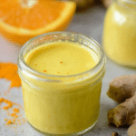Homemade lemon ginger turmeric shot in a jar with lemons and ginger