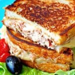 The perfect tuna melt with golden toasted bread and melted mozzarella cheese, sliced in half to reveal the creamy tuna filling.