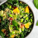 A vibrant kale quinoa salad featuring mango, tomatoes, avocado, and almonds, perfect for healthy meal prep.
