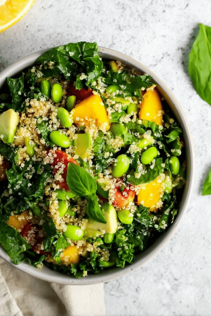 A vibrant kale quinoa salad featuring mango, tomatoes, avocado, and almonds, perfect for healthy meal prep.