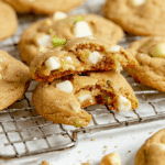 Freshly baked key lime white chocolate macadamia nut cookies on a plate, decorated with lime slices and macadamia nuts.