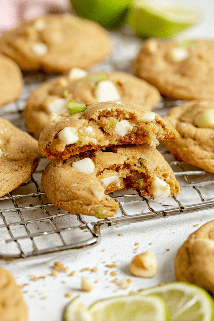 Freshly baked key lime white chocolate macadamia nut cookies on a plate, decorated with lime slices and macadamia nuts.
