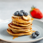 Colorful stack of kid-friendly banana pancakes topped with fresh sliced bananas and maple syrup, perfect for a nutritious breakfast.