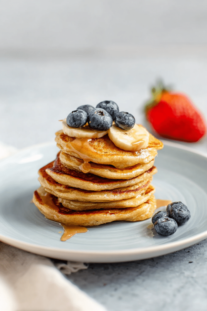 Colorful stack of kid-friendly banana pancakes topped with fresh sliced bananas and maple syrup, perfect for a nutritious breakfast.