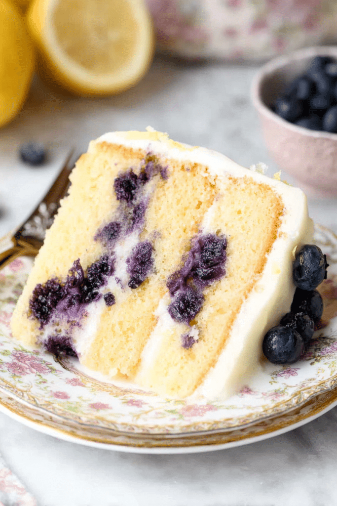 Lemon blueberry cake garnished with blueberries and lemon slices on a rustic wooden table.
