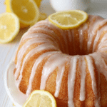 Delicious lemon bundt cake with lemon glaze and slices displayed on a wooden table.