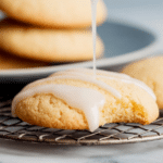 Plate of lemon cookies with lemon glaze and fresh lemons on a wooden table