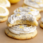 Close-up of lemon poppy seed cheesecake cookies topped with cream cheese frosting, surrounded by lemon slices and poppy seeds.