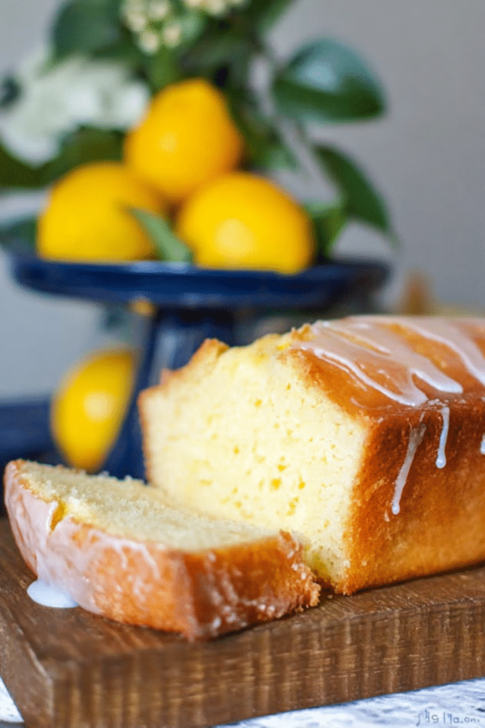 Lemon pound cake served on a wooden table with lemon slices and fresh mint, perfect for summer brunch.