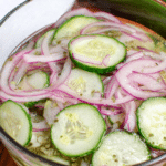 Old fashioned cucumber salad served in a decorative bowl with fresh cucumbers, red onions, and dill, showcasing a colorful and appetizing presentation.