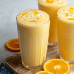 Refreshing orange creamsicle smoothie in a tall glass with orange garnish on a wooden table