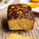 Paleo orange kissed loaf with dark chocolate glaze and fresh orange zest on a wooden table