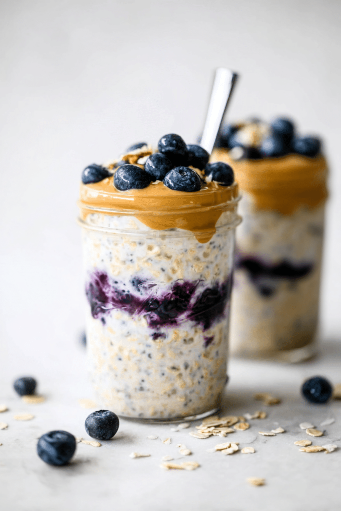 Peanut butter blueberry overnight oats in a mason jar topped with fresh blueberries on a rustic wooden table.