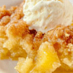 Delicious pineapple dump cake served with vanilla ice cream and cherry on top.