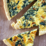 Freshly baked Quiche Florentine with spinach and cheese displayed on a rustic wooden table.