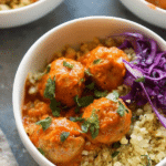 Red coconut curry meatballs served with cauliflower rice, garnished with cilantro and lime, capturing the essence of Thai cuisine.