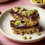 Close-up of salted dark chocolate pistachio quinoa crunch bar with chopped pistachios and sea salt.