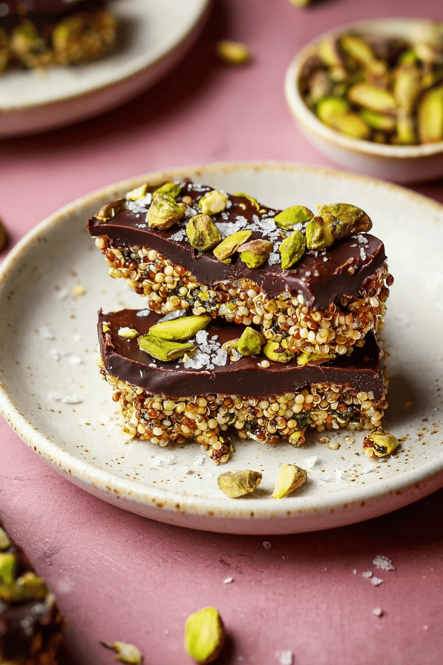 Close-up of salted dark chocolate pistachio quinoa crunch bar with chopped pistachios and sea salt.