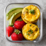 Savory chicken sausage egg and cheese muffins served with avocado and salsa on a wooden table.