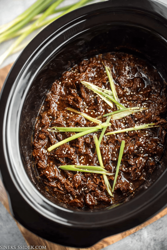 Delicious slow cooker Korean beef served over rice with vegetables, garnished with sesame seeds and scallions.