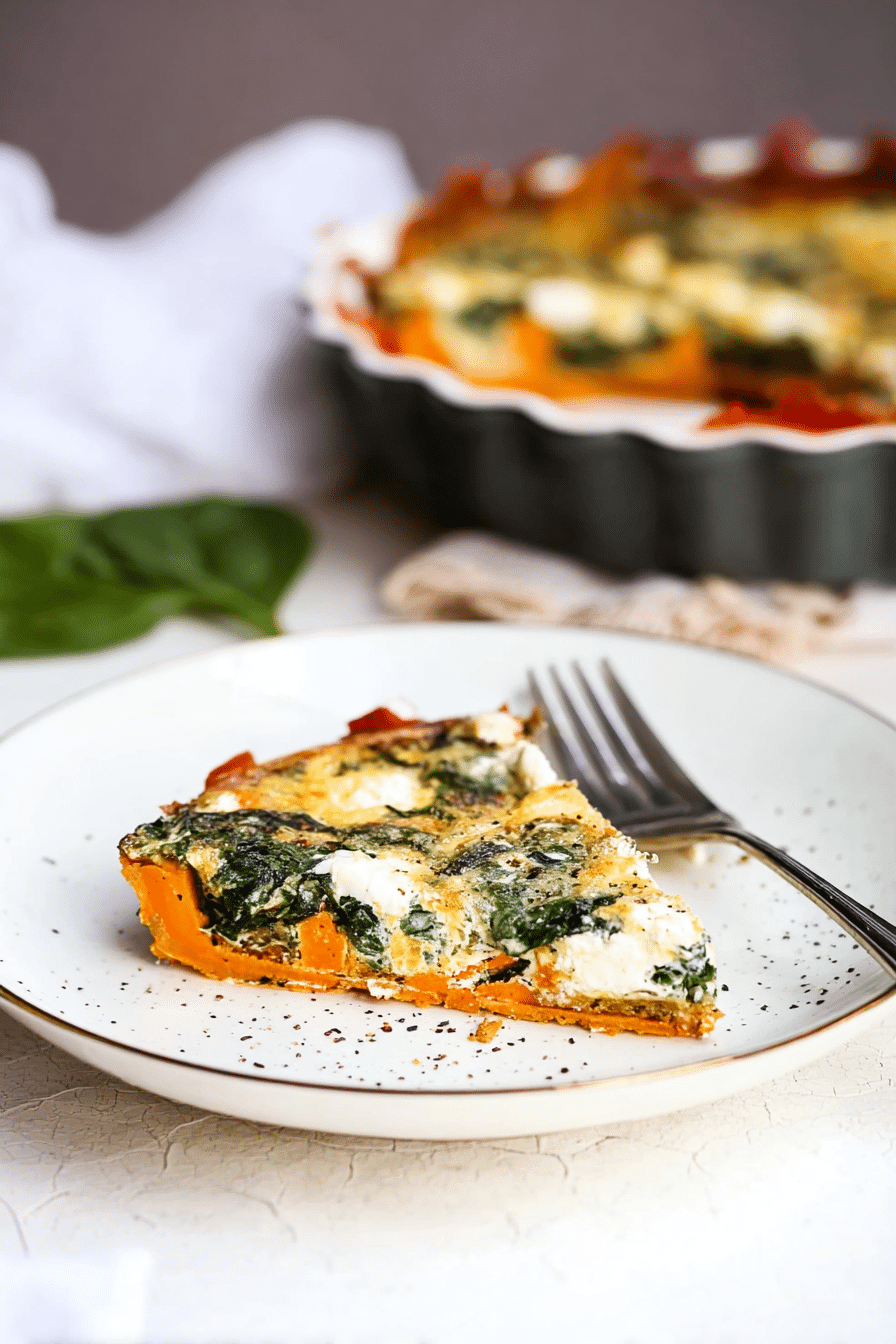 A slice of spinach and goat cheese quiche on a wooden table, accompanied by a fresh salad, showcasing the dish's colorful ingredients and healthy presentation.