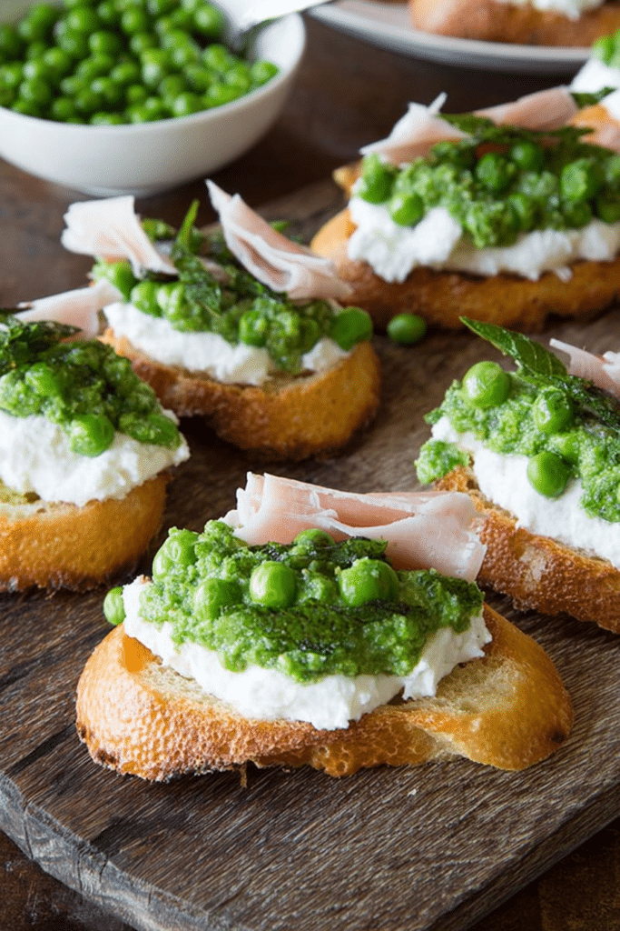 Close-up of spring pea crostini with burrata and prosciutto on a wooden board