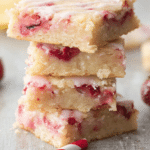 A delicious slice of strawberry lemon blondie on a wooden table, garnished with fresh strawberries and a lemon.