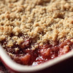 Delicious strawberry rhubarb crumble topped with a golden crumble and served with vanilla ice cream.