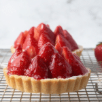 A delectable strawberry tart featuring a buttery crust and topped with fresh strawberries, showcasing a glossy fruit glaze in natural light.