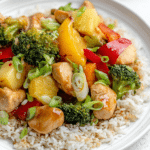 Sweet and sour pineapple broccoli chicken stir fry with chicken, broccoli, and pineapple in a bowl, topped with scallions.