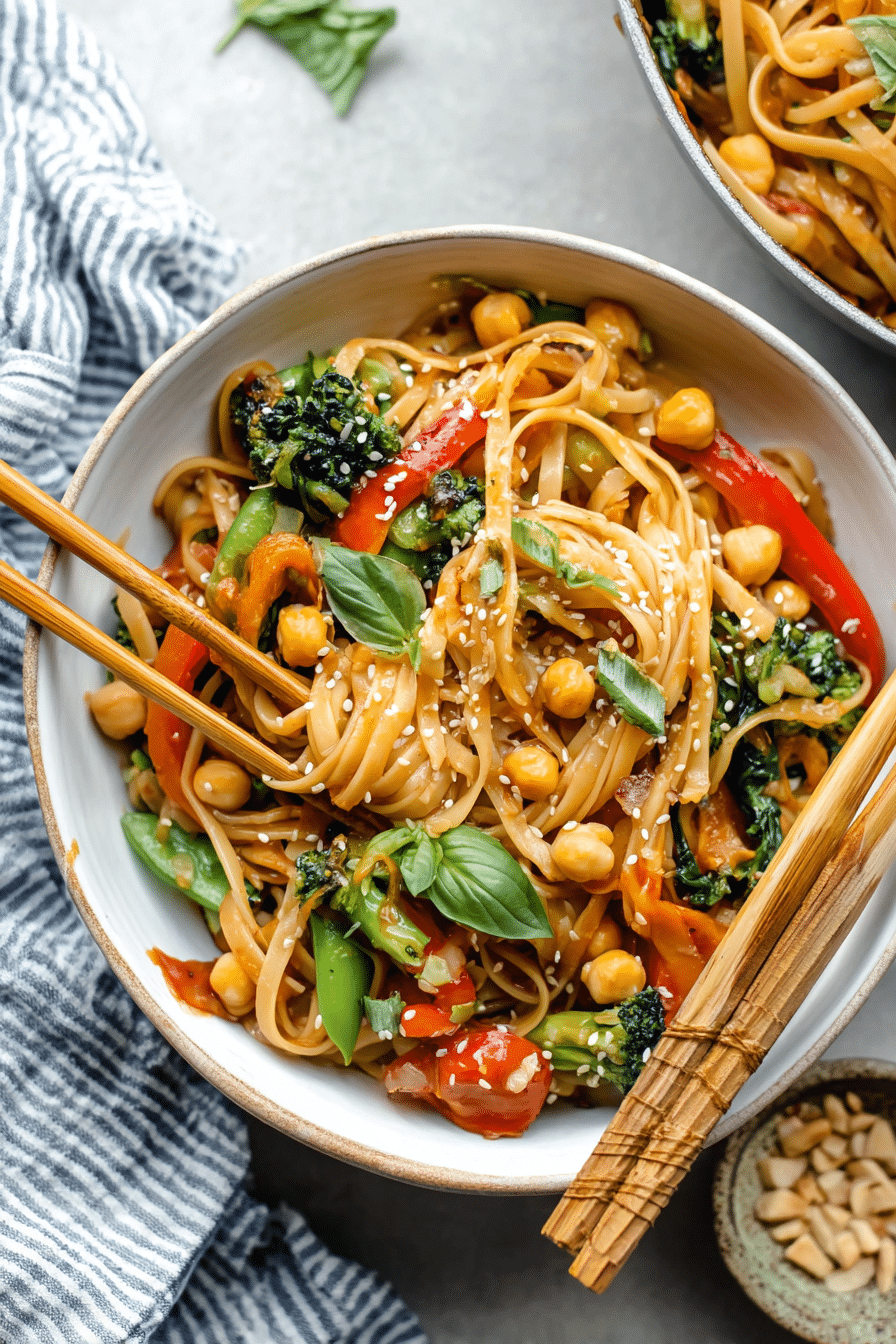 A vibrant bowl of 30-minute vegan stir fry sesame noodles garnished with basil and chopped cashews.