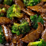 Beef and broccoli stir fry in a bowl with sesame seeds and rice, showcasing a colorful and appetizing dinner dish.