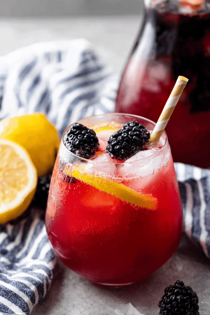 Refreshing blackberry lemonade in a glass with ice and garnishes of lemon slices and blackberries.
