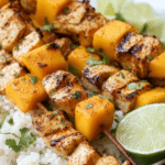 Grilled chili-lime mango chicken skewers served with cilantro and lime wedges, highlighting the vibrant colors and appetizing presentation.