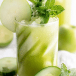 Refreshing cucumber mint cooler in a glass on a wooden table, garnished with cucumber slices and mint leaves.