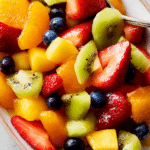 Bright and colorful fruit salad with strawberries, blueberries, kiwi, and mandarin oranges in a bowl.