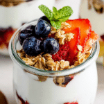 Delicious Greek yogurt parfait layered with fresh berries and crunchy granola in a glass jar.