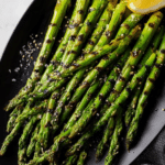 Deliciously grilled asparagus garnished with lemon wedges on a wooden table.