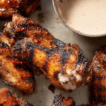 Crispy grilled chicken wings with a flavorful dry rub served with dipping sauce and herbs.