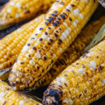 Grilled corn on the cob with butter and salt on a wooden table