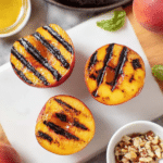 Delicious grilled peaches topped with vanilla ice cream and crushed walnuts, perfect summer dessert.