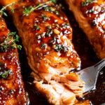 Plate of honey garlic glazed salmon with vegetables and lemon, garnished with parsley.