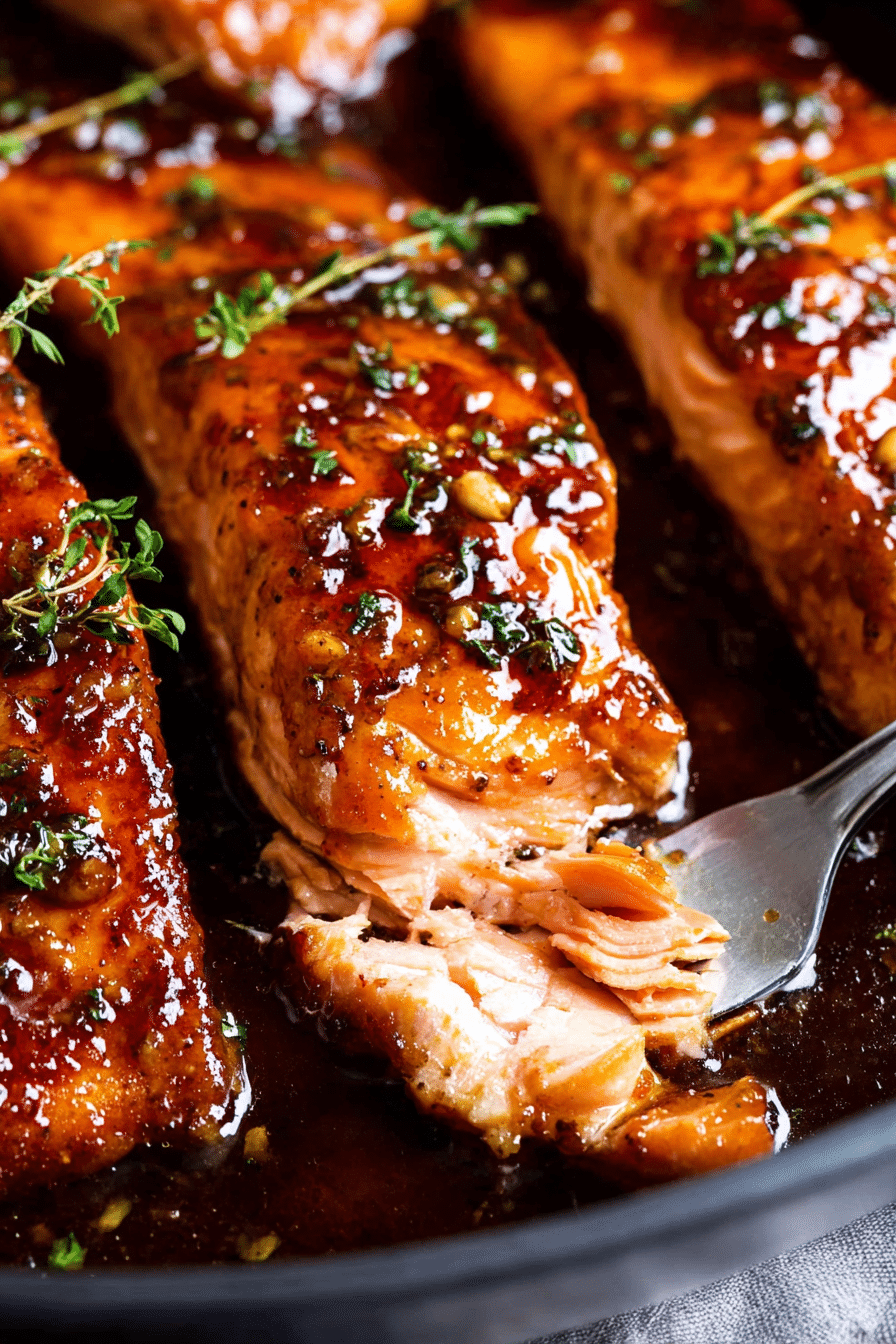 Plate of honey garlic glazed salmon with vegetables and lemon, garnished with parsley.
