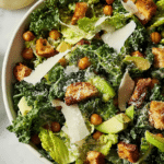 Vibrant kale Caesar salad with croutons and avocado in a wooden bowl