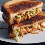 Kimchi grilled cheese sandwich showcasing melted cheese and kimchi, served with pickles.