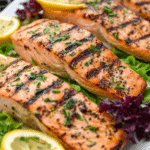 Lemon garlic herb grilled salmon garnished with parsley and lemon on a wooden table.