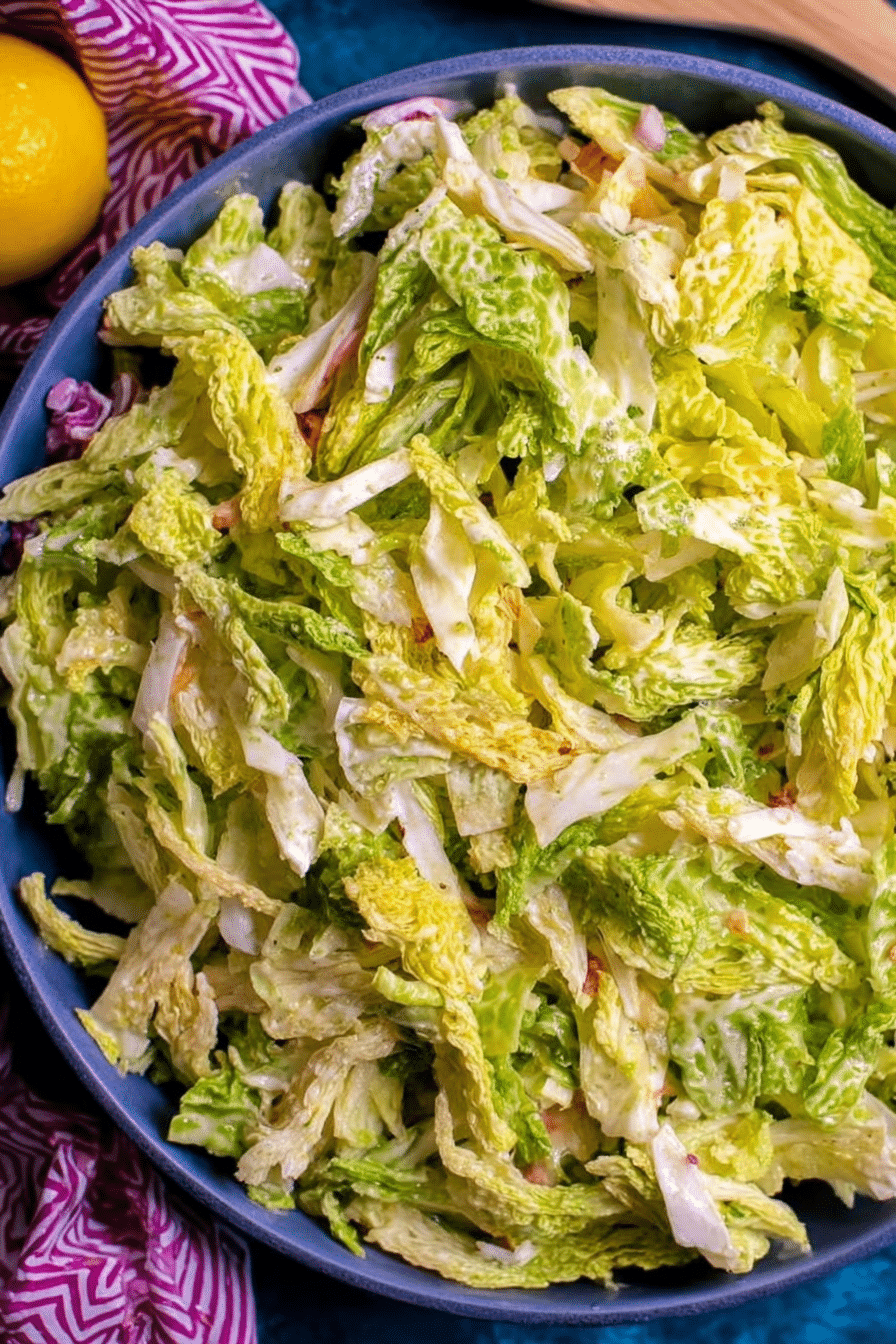 Lemony Savoy cabbage salad in a rustic bowl with fresh herbs and lemons.