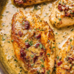 Creamy Marry Me Chicken served over pasta, garnished with fresh basil and sundried tomatoes.